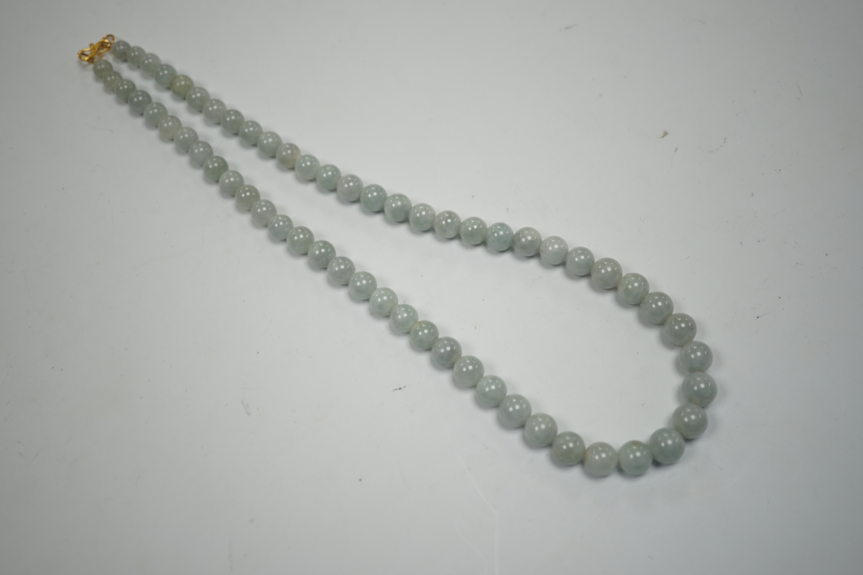 A single strand graduated jade bead necklace, with high carat yellow metal clasp, 46cm.